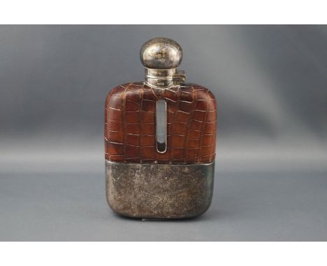 A clear glass oblong hip flask with crocodile effect brown leather mounts and a plated hinged cover and cup, 14cm high overal