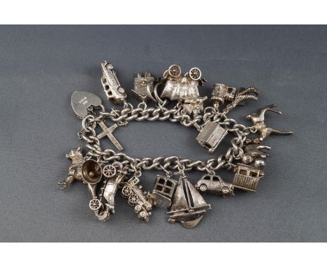 A silver curb link charm bracelet on a padlock clasp, Birmingham 1965, and hung with numerous charms including a London taxi,