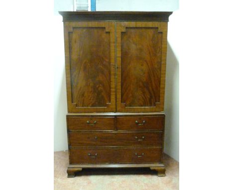 Georgian mahogany wardrobe on chest, formerly a linen press, with moulded cornice above two doors enclosing a later hanging r