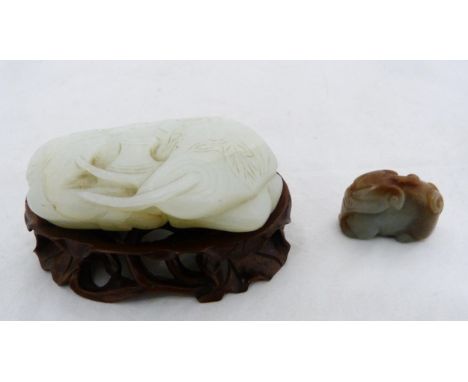 Chinese celadon jade carving of a recumbent kylin, Qing Dynasty, on a padouk stand, 9cm, and another Chinese brown jade carvi
