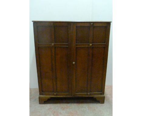Waring &amp; Gillow Ltd (Liverpool) Oak gentleman's cupboard with two panelled doors enclosing a hanging rail to one section 
