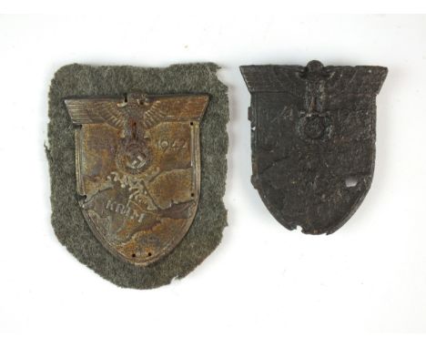 Two Third Reich German Army/Waffen-SS Krim metal arm shields, in relic condition. One shield with original cloth backing. (2)
