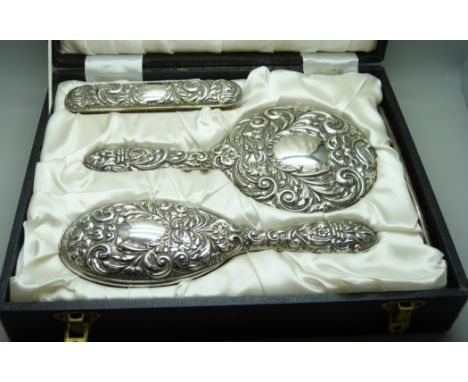 An embossed silver vanity set in a fitted case 