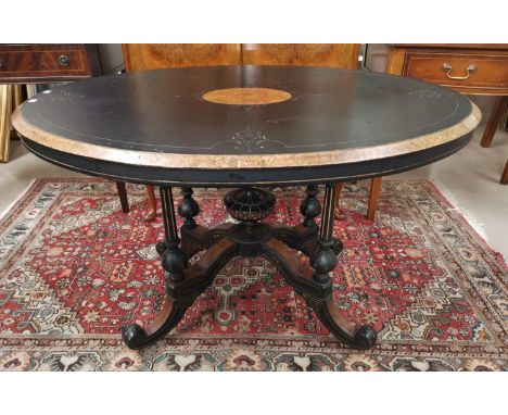 A late Victorian ebonised and burr walnut centre table with oval top, incised gilded decoration, on quatrefoil base with cera