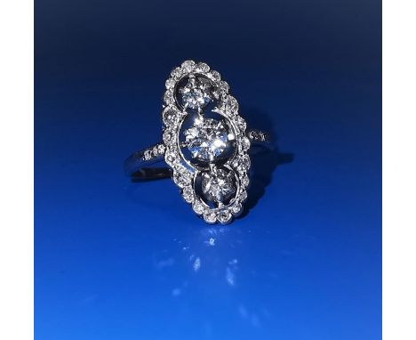An Art Deco period dress ring of elongated oval form, on white metal shank, set vertically with 3 central diamonds and 22 sma