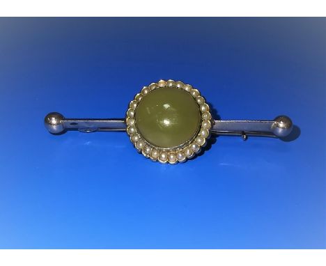 A yellow metal bar brooch set circular domed jade coloured stone surrounded with seed pearls, unmarked, tests as circa 9 ct, 