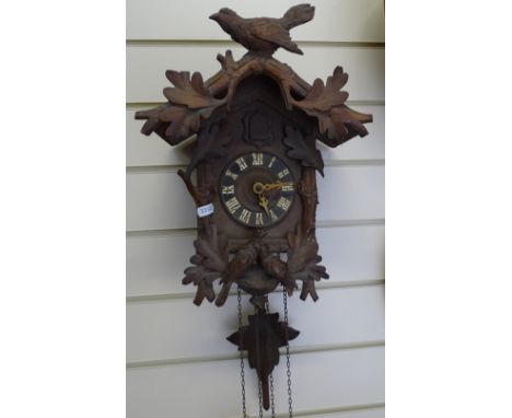 A Vintage German Black Forest cuckoo clock, bird and leaf decorated case with pine cone weights and pendulum, case height 37c