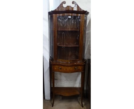 A late Victorian mahogany and satinwood-strung serpentine-front 2-section cabinet, the top having a swan-neck pediment above 