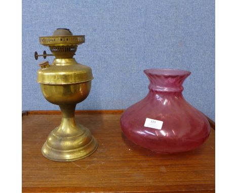 A brass oil lamp, with cranberry glass shade 