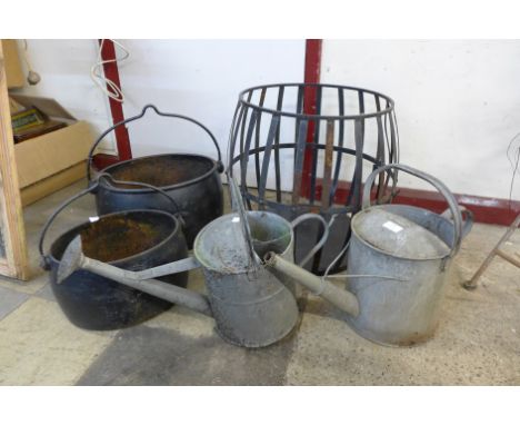 Two cast iron cauldrons, a wrought iron planter and two galvanised watering cans 