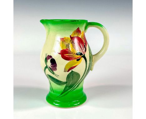 A small handled pitcher, decorated with hand painted large flowers and their foliage against an ivory and green colored groun