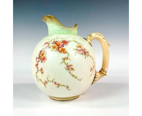A small, bulbous pitcher featuring a floral vine design with gold decoration throughout, on a soft green and white colored gr