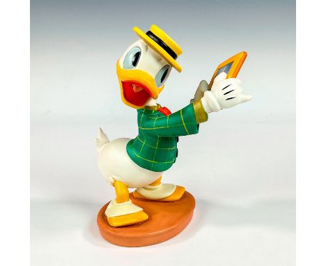 Porcelain figure with matte finish. Depicts Donald Duck in a green coat and yellow boater hat, admiring a portrait of Daisy D