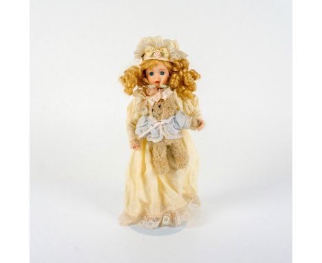 A curly blonde-hair doll crafted with a resin face, hands, and feet; dressed in a cream-color nightgown and nightcap with lac