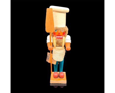 Hand-carved and hand-painted wooden nut cracker modeled as a bearded pizzaiolo with large pizza peel and gingham apron. Nutcr