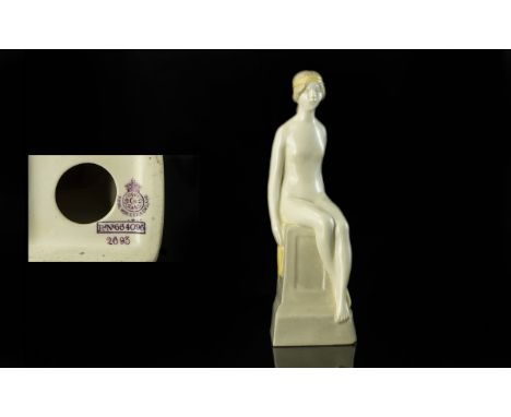 A Royal Worcester Earthenware Figure of a Naked Maiden, 1918,  holding a shoe, seated on a pedestal, puce mark RD No. 664096,