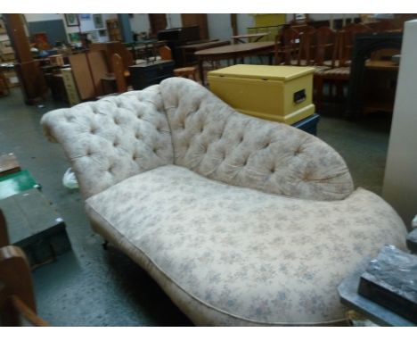 A Victorian chaise longue, button back with floral cover raised on turned legs and castors