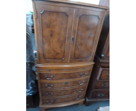 A 20th century walnut cabinet on chest, two cupboards over four long drawers with slide panel, raised on shaped bracket feet,