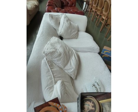 A modern three seater sofa with removable white cotton covers and feather filled cushions.