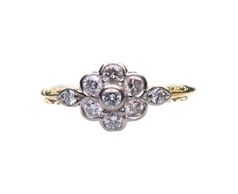 AN 18 CARAT GOLD DIAMOND CLUSTER RING a cluster of seven round brilliant-cut diamonds, to diamond-set shoulders in a carved s