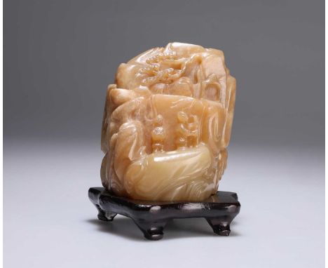A CHINESE JADE BOULDER CARVING carved in the round, depicting figures on a rocky outcrop, on a wooden stand. 11cm high overal