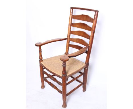 An 18th Century elm ladder back arm chair, with a rush seat.