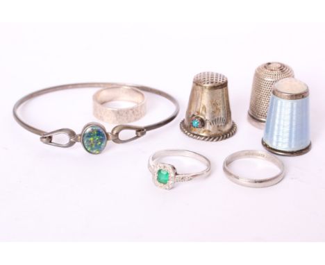 A collection of silver and white metal items to include a diamond and emerald ring, two sterling silver bands, a white metal 