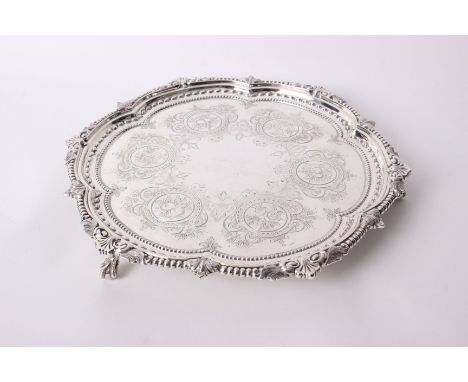 A Victorian silver salver with leaf and bead decorated border, the plate engraved with leaves and scrolls, raised on ball and