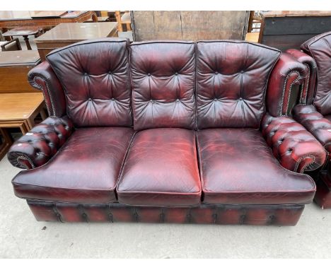 AN OXBLOOD LEATHER THREE SEATER SOFA WITH BUTTONED BACK AND ARMS 