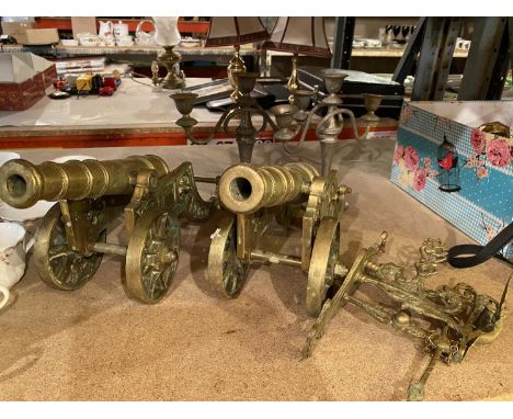 TWO LARGE BRASS CANNONS AND TWO CANDELABRAS PLUS A DECORATIVE HANGING DOOR KNOCKER 