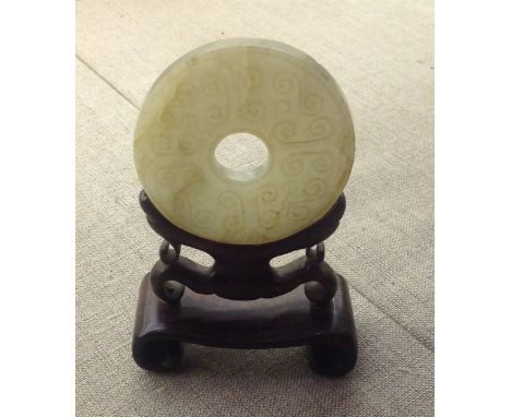 AN ANTIQUE CHINESE PALE JADE BI Raised on a hardwood stand. 