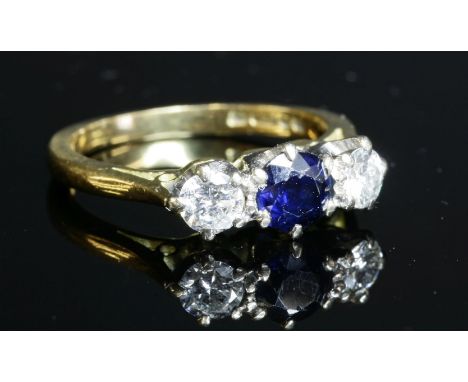 An 18ct gold sapphire and diamond three stone ring, c.1970,by Len Wilson Jewellery.  A circular mixed cut sapphire, claw set 