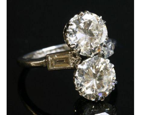 An Art Deco two stone diamond fingerline ring,with baguette cut diamond shoulders.  Two brilliant cut diamonds, double claw s