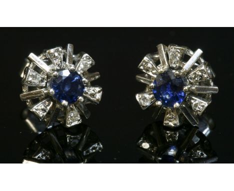 A pair of 18ct white gold sapphire and diamond cluster earrings, with a circular mixed cut sapphire, claw set to the centre. 