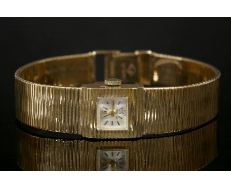 A ladies' 9ct gold Swiss mechanical bracelet watch, with a square case, silvered dial and gilt hands and batons.  Integral br