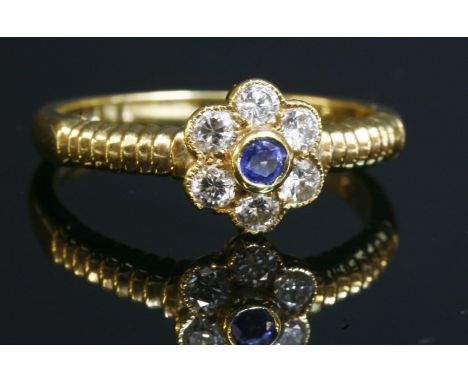 An 18ct gold sapphire and diamond daisy cluster ring,with a central circular mixed cut sapphire, with a stated weight of 0.32