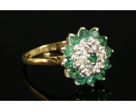 A gold, emerald and diamond three-tier cluster ring,to chenier shoulders and a plain polished shank.  Marked 18ct.  4.39g.Fin