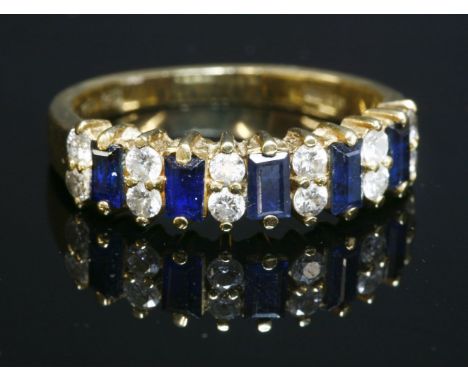 An 18ct gold sapphire and diamond half hoop ring,with a row of baguette cut sapphires, with pairs of brilliant cut diamonds b