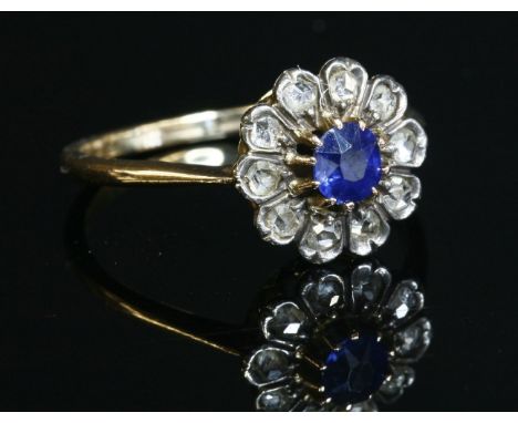 A sapphire and diamond circular cluster ring,with a circular Swiss cut sapphire, claw set to the centre.  Surrounded by white