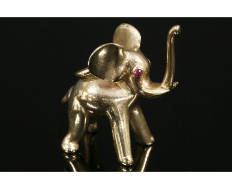 A 9ct gold novelty elephant charm/pendant, London 1968,with ruby eyes and trunk held aloft.  23 x 14mm approximately, 22.60g