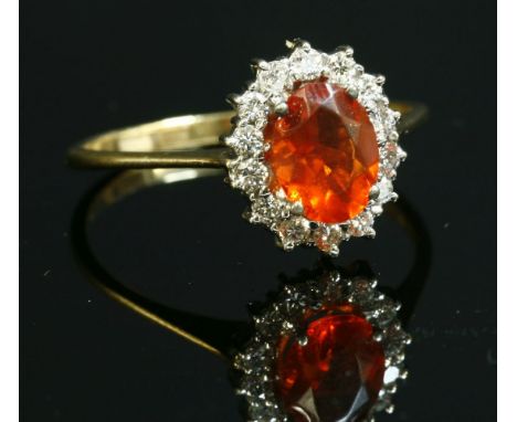 An 18ct gold, fire opal and diamond oval cluster ring,with an oval mixed cut fire opal, four claw set to the centre.  A borde