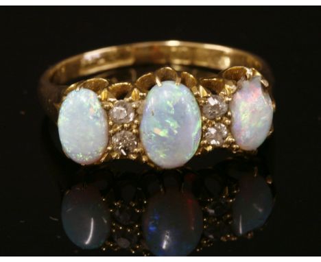 An 18ct gold Edwardian opal and diamond ring,with three graduated oval cabochon opals, all claw set to scalloped claw.  Pairs