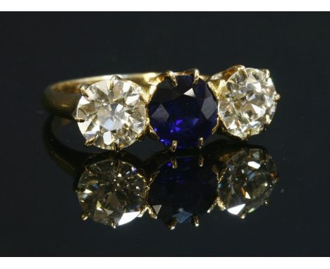 A three stone sapphire and diamond ring,with a central, circular mixed cut sapphire, claw set to the centre.  An old European