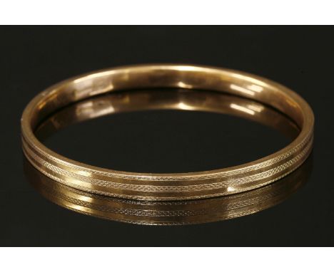 An Art Deco 9ct gold hollow flat section slave bangle, with engine turned decoration, London 1922.  6.5mm wide, 71mm internal