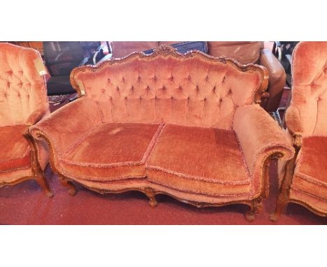 An early 20th Century French walnut two seater sofa having carved floral frame with pink velour button back upholstery, raise