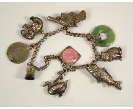 CHARM BRACELET. A child's silver charm bracelet, hung a variety of charms, including a Chinese pistol compass fob.