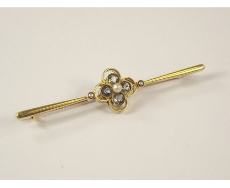 AQUAMARINE PIN. A 15ct. gold bar brooch, the central quatrefoil set with aquamarine, a pearl &amp; seed pearls. 6.5cm.