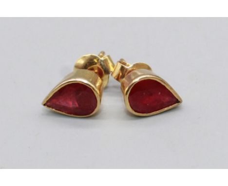 Pair of yellow metal ruby earrings, the teardrop cut rubies in rub over settings, one back stamped 9ct, the rest unmarked, 2.