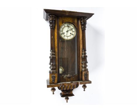 A late 19th/early 20th Century drop dial wall clock, white enamel dial with Roman numerals, in a walnut case with part turned