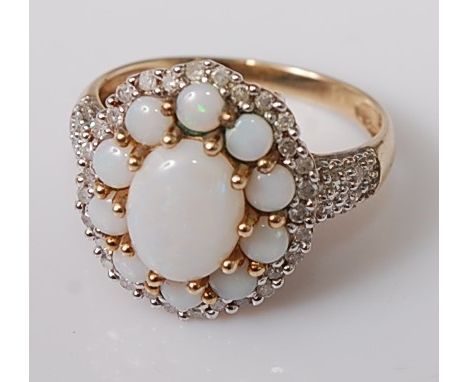 A 9ct gold opal and diamond dress ring, the large oval setting having a centre cabochon opal flanked with small round opals a